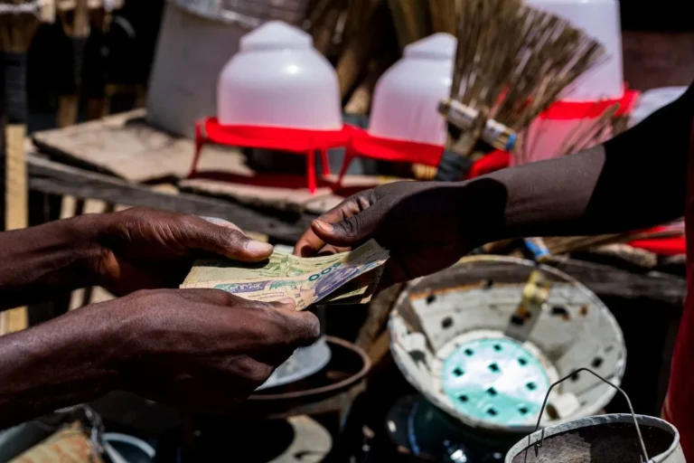 Stock photograph of hands exchanging banknotes at an outdoor market; the people and transaction shown are unaffiliated with Wanhoo
