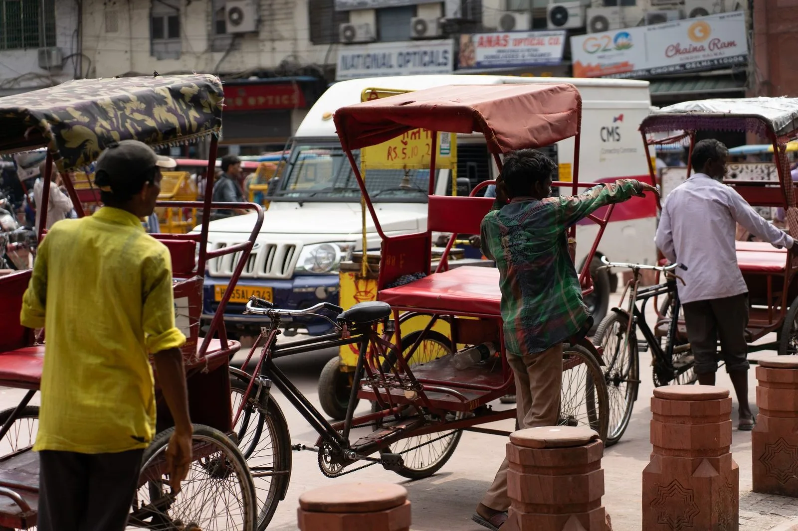 Stock photograph of a crowded street with auto-rickshaws, pedestrians and roadside stalls; the people and vehicles are unaffiliated with Wanhoo