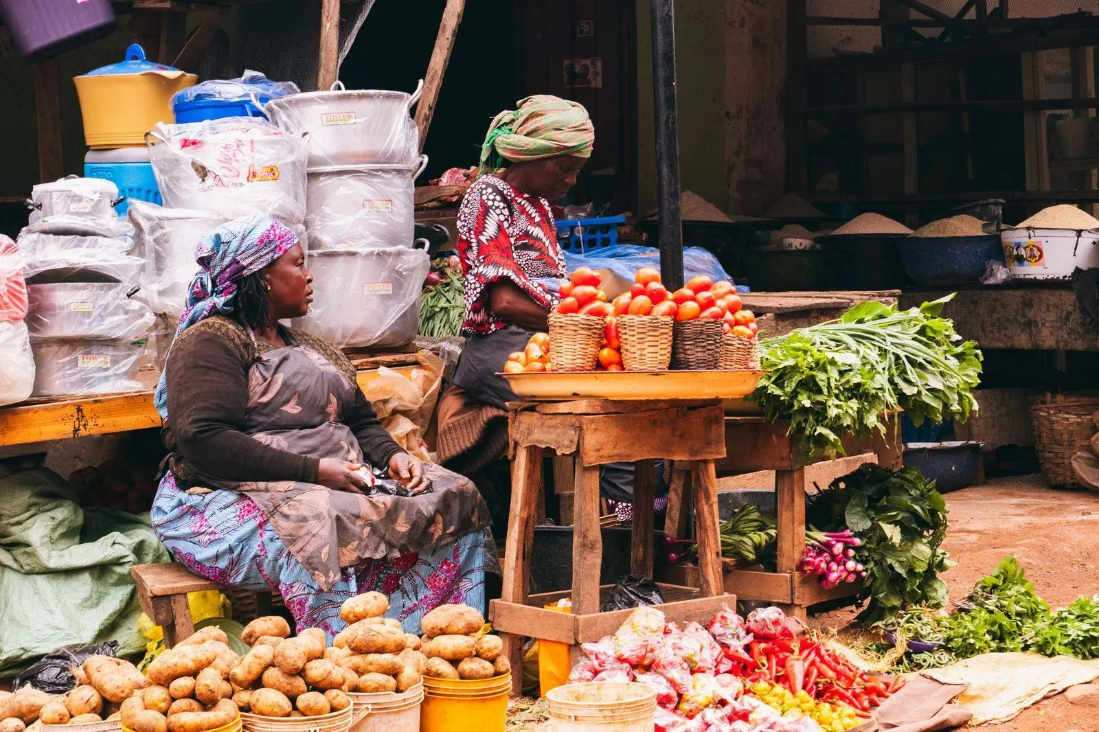 Stock photograph of traders beside baskets and crates of vegetables at an open-air market; the people and market are unaffiliated with Wanhoo