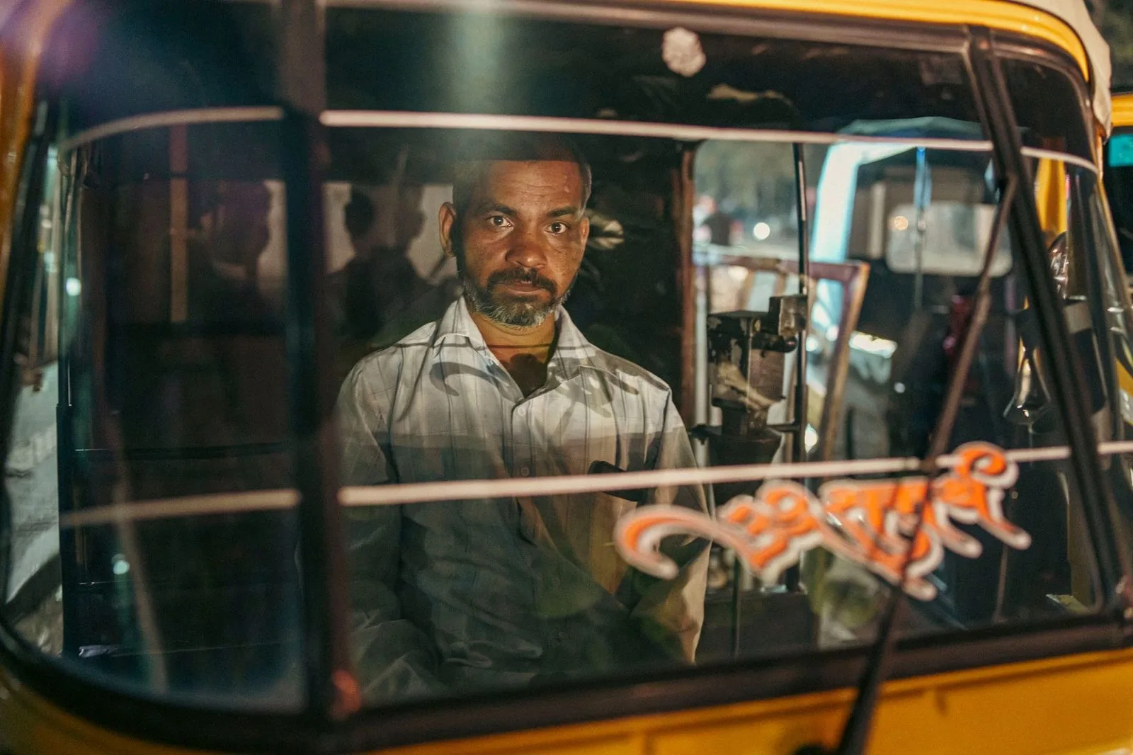 Stock photograph of a person driving an auto rickshaw in Pune; the person and vehicle shown are unaffiliated with Wanhoo