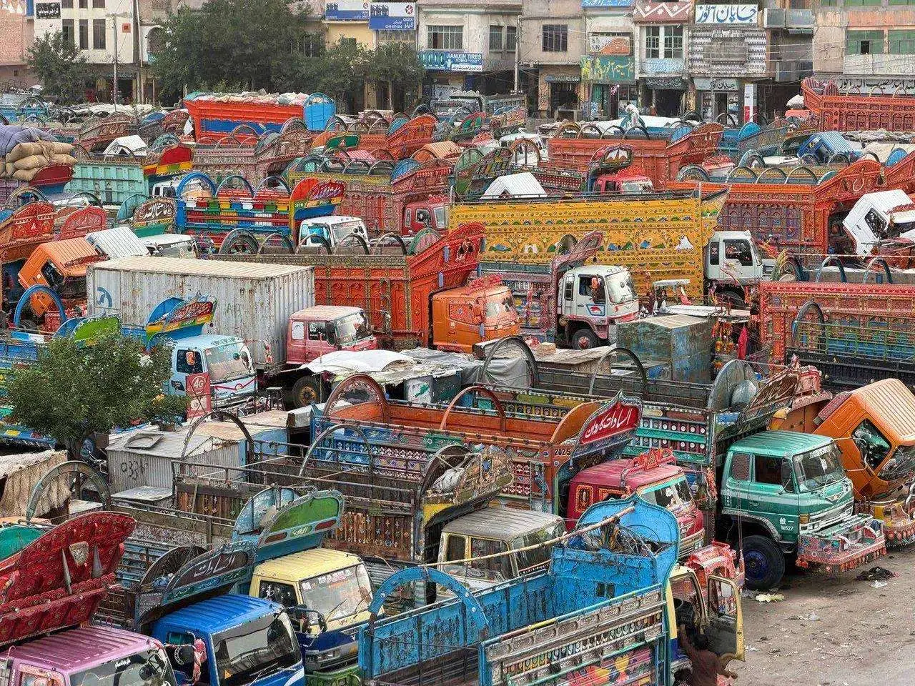 Stock photograph of hand-painted commercial vehicles parked together in a vehicle yard; the vehicles and people are unaffiliated with Wanhoo