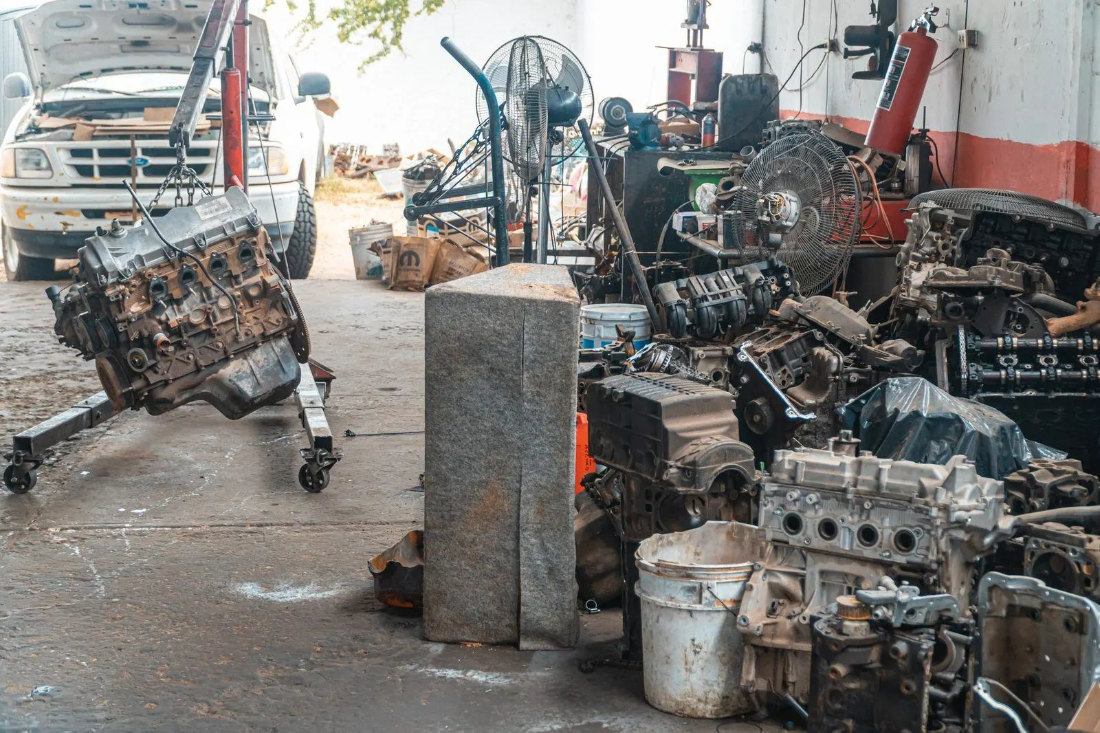 Stock photograph of dismantled automotive engines and components inside a repair workshop; the workshop is unaffiliated with Wanhoo