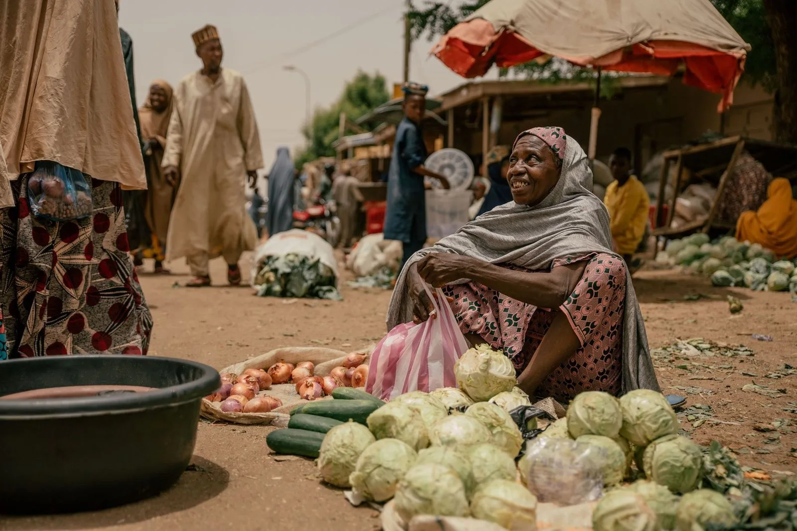 Stock photograph of a woman running a produce stall at an open-air market; the person and business are unaffiliated with Wanhoo