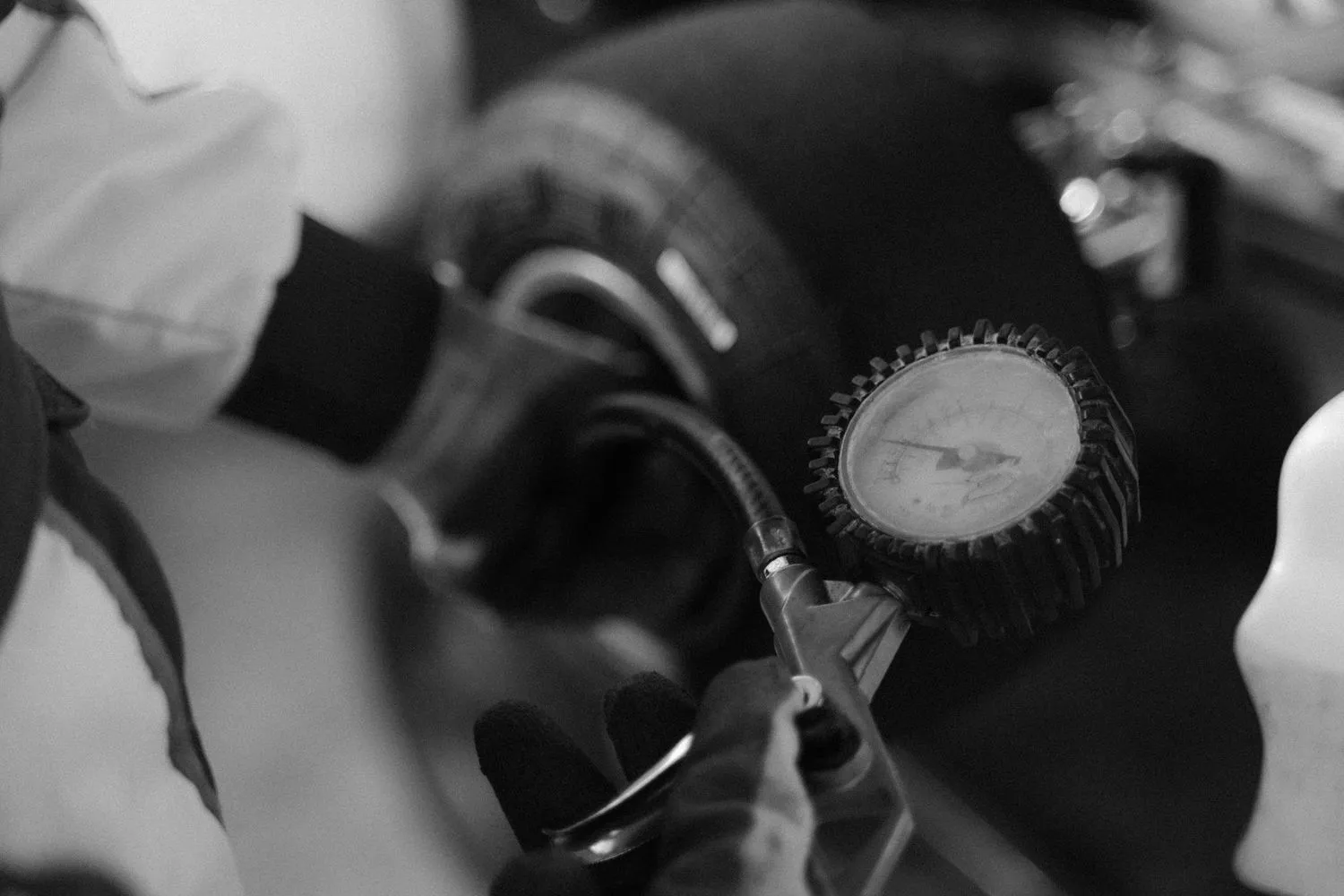 Stock photograph of a mechanic checking tyre pressure with a gauge; unaffiliated with Wanhoo