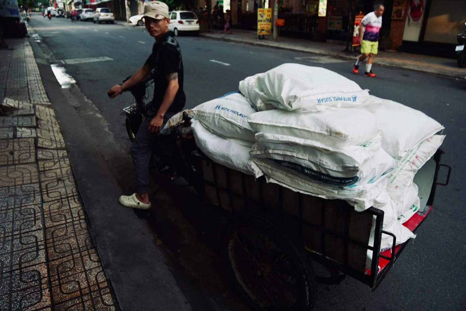 Stock photograph of a three-wheeled goods vehicle carrying sacks on a city street; unaffiliated with Wanhoo
