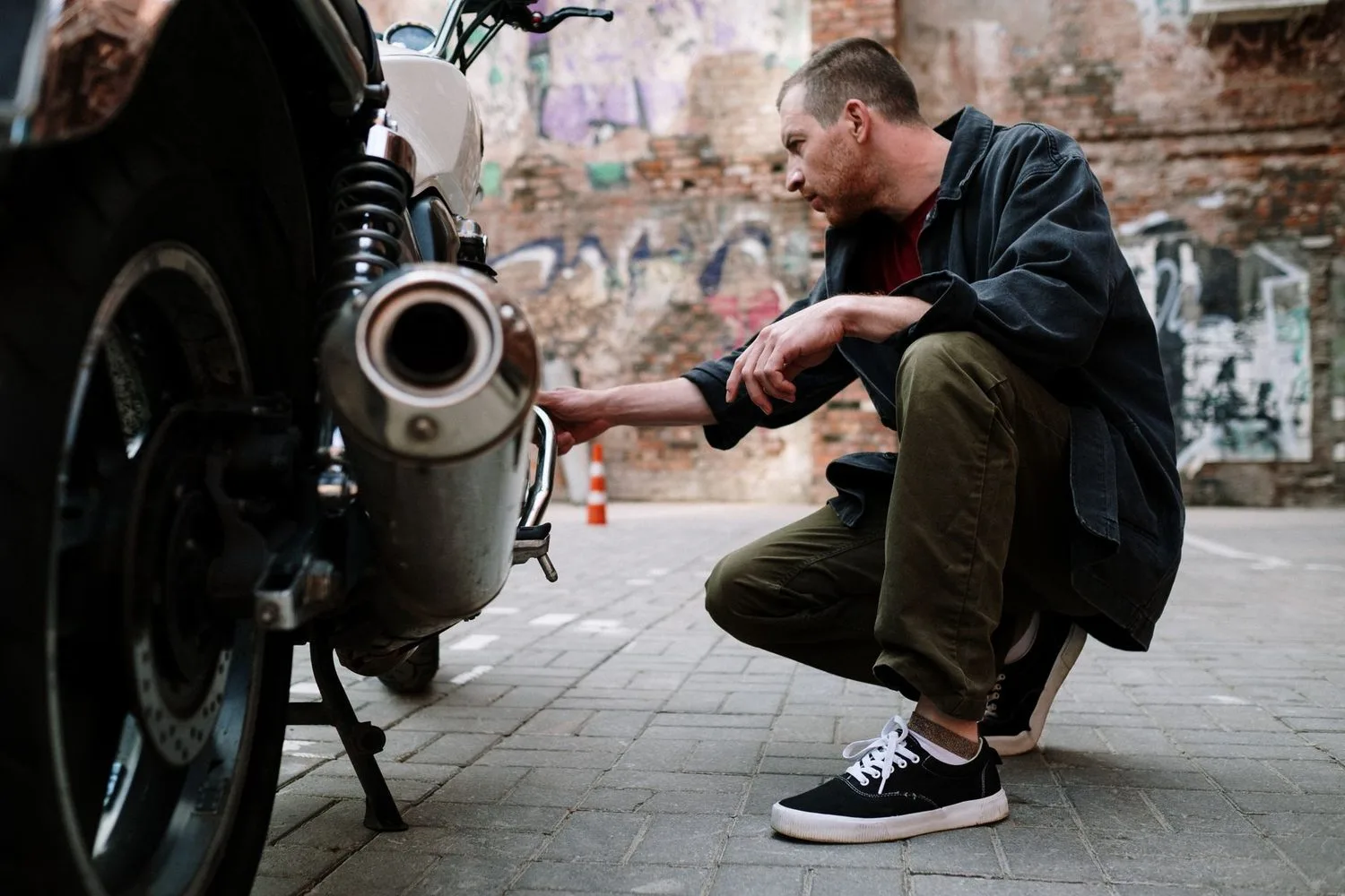 Stock photograph, unaffiliated with Wanhoo: a mechanic crouching to inspect a vehicle before a decision is made