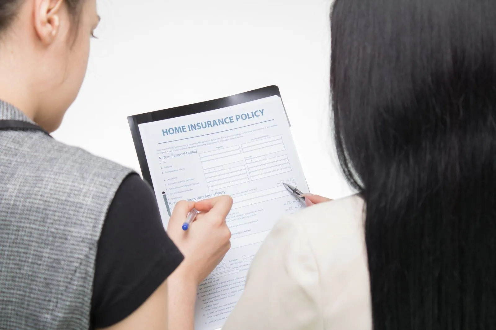 Pexels stock photograph by Mikhail Nilov, unaffiliated with Wanhoo, showing two people reading a home-insurance form as a generic policy-review illustration