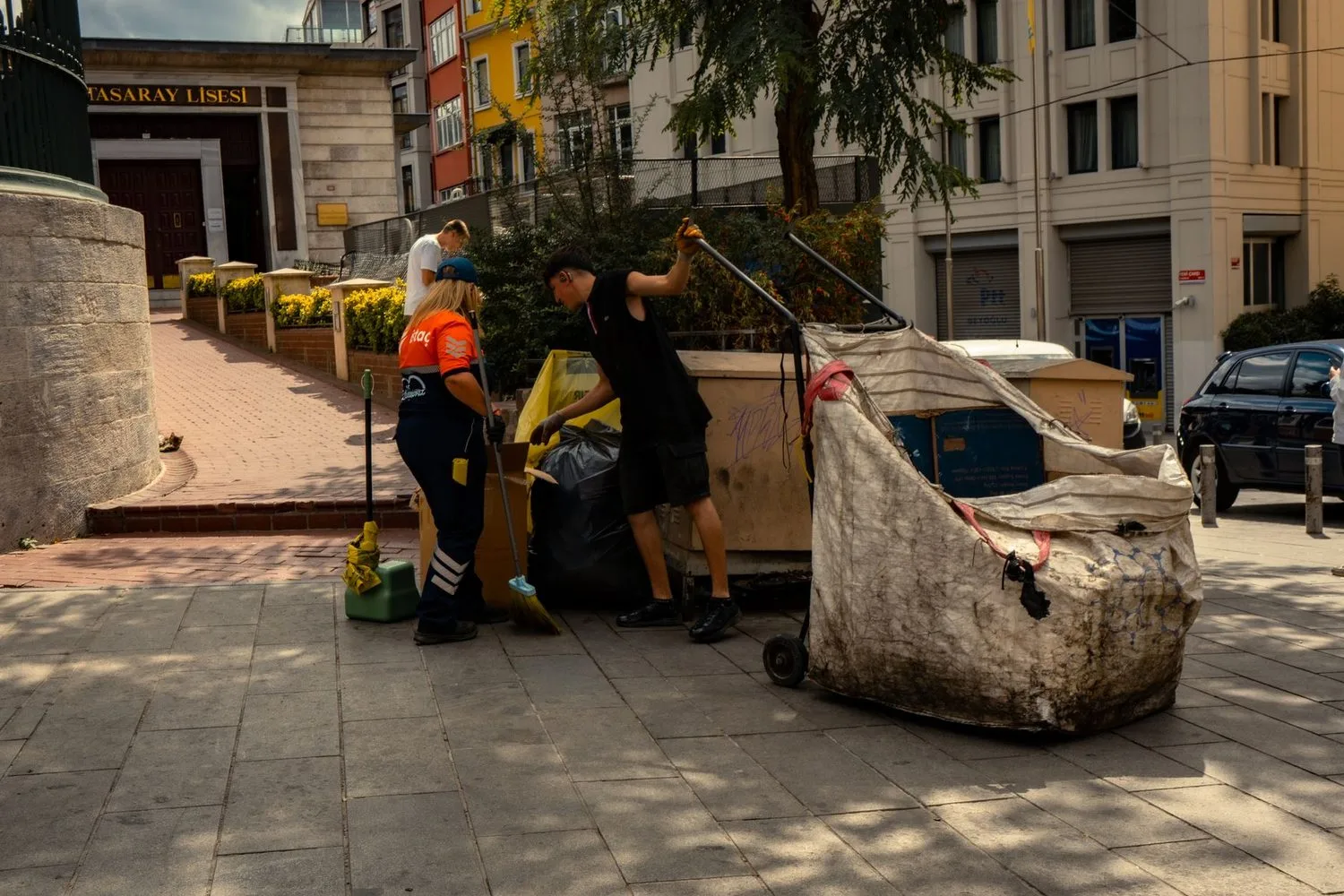 Stock photograph, unaffiliated with Wanhoo: sanitation workers collecting waste on a city street