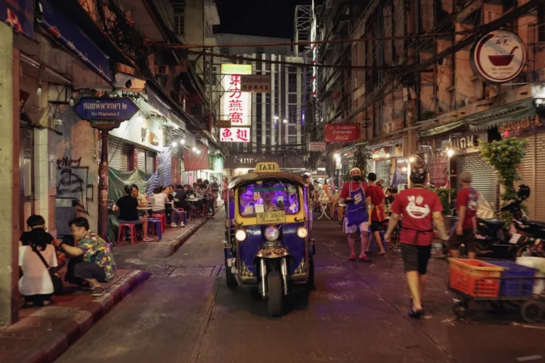 Stock photograph of a three-wheeler in a lit city alley after dark; unaffiliated with Wanhoo