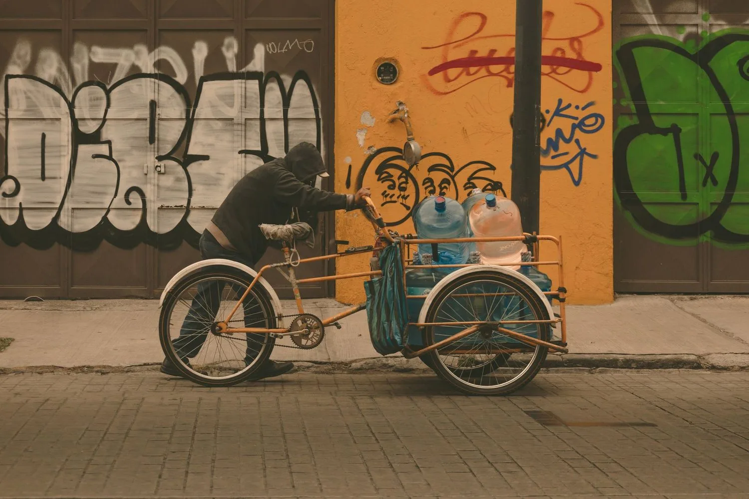 Stock photograph, unaffiliated with Wanhoo: water containers being moved by a three-wheeled cycle through a city street